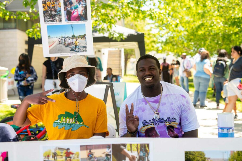 A young Black woman and man tabling at a fair and smiling